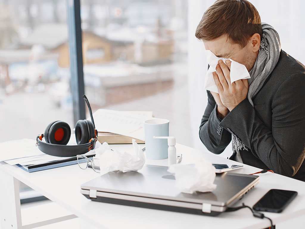 Man with a laptop is suffering with cough and feeling bad. Businessman at home.