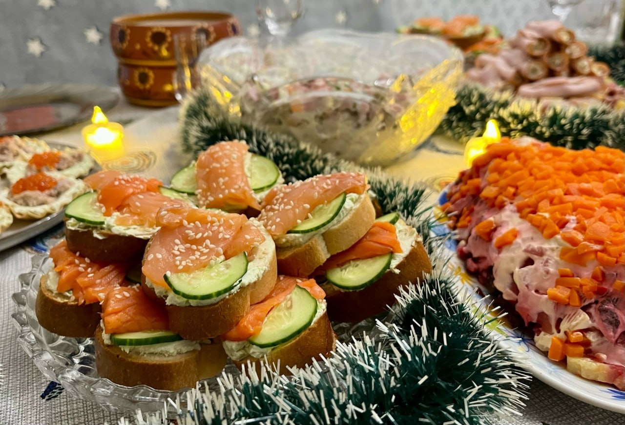 Праздничный стол с домашними закусками и салатами как пример привычки готовить дома для здоровья мозга.